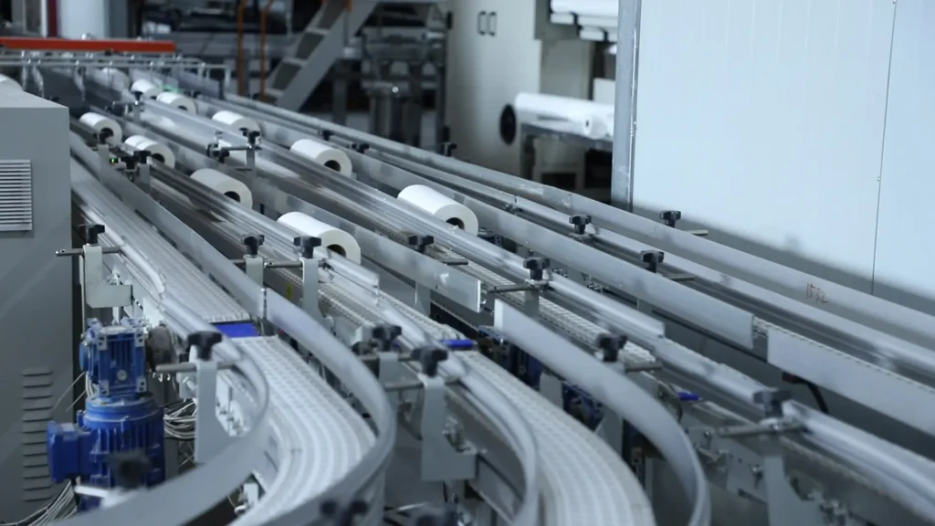 Parent jumbo rolls being rewound and cut into smaller rolls in step 7 of the bamboo tissue manufacturing process